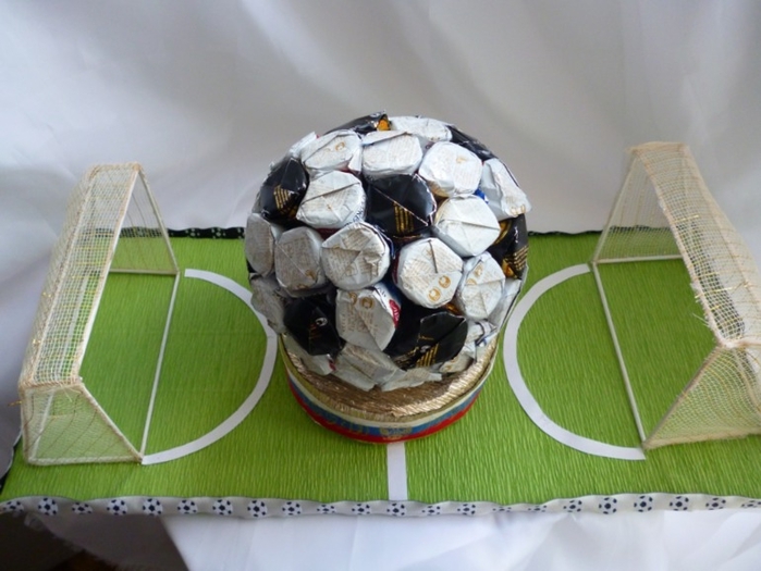 Футбольный мяч из конфет на футбольном поле.